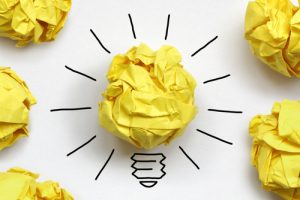 A crumpled up piece of yellow paper, decorated to look like a lightbulb