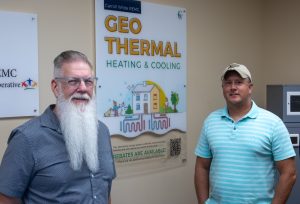 Two men standing in front of geothermal program sign.